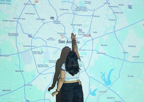 A student places a sticky note on a projected map of San Antonio.